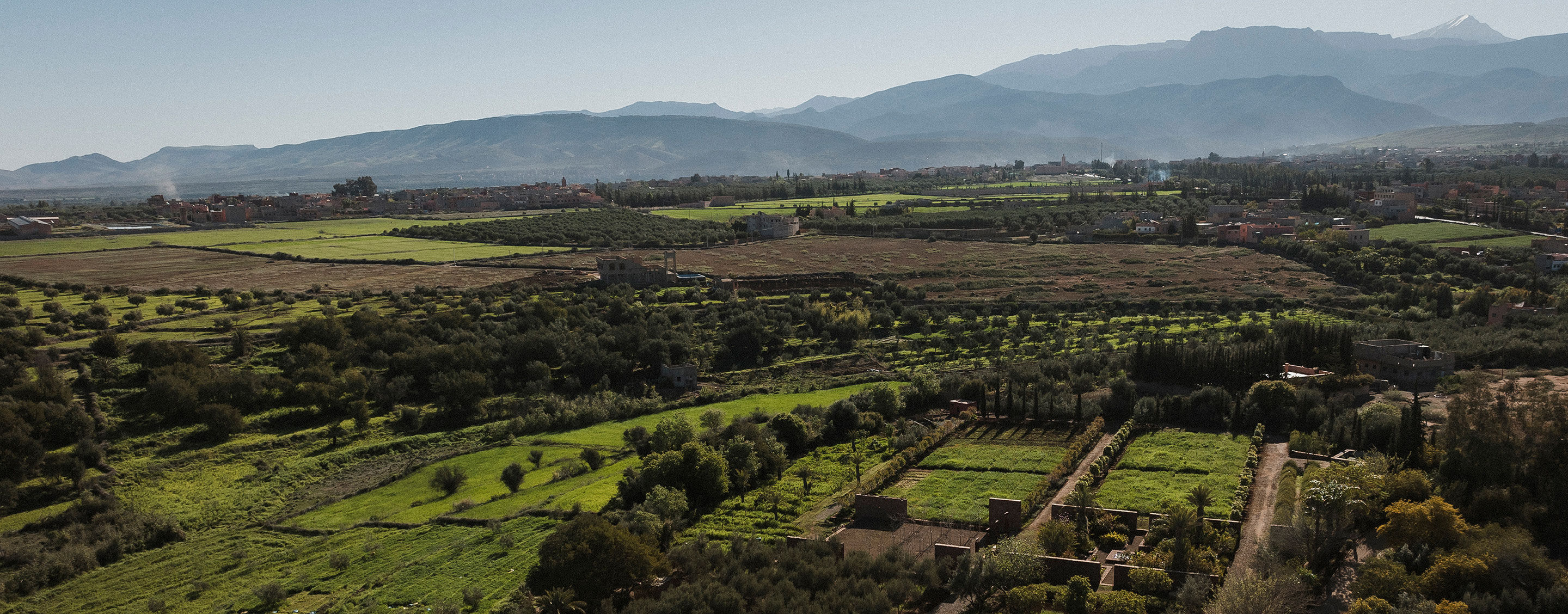 Ourika Gardens, with lush green fields, and distant mountains.